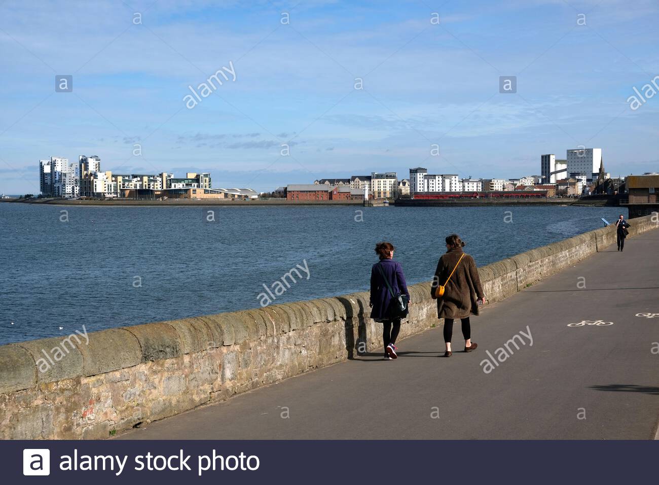 La gente su Mckelvie parata a Granton presso la riva, con una vista verso Newhaven e lo sviluppo moderno a Leith, Edimburgo, Scozia Foto Stock