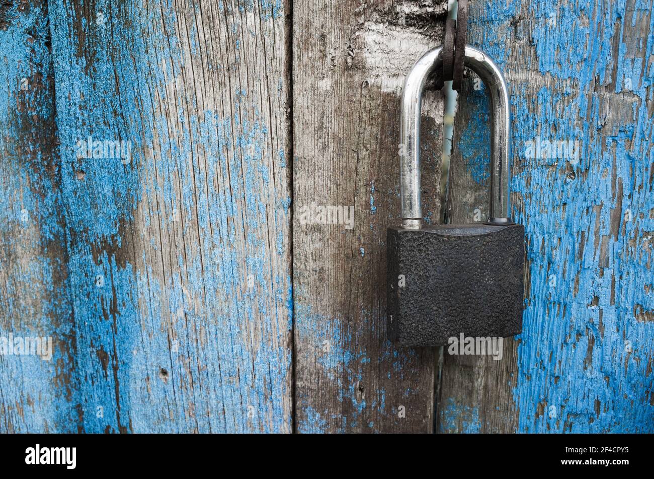 Lucchetto appeso su una porta di legno blu grugnante. Primo piano della foto Foto Stock