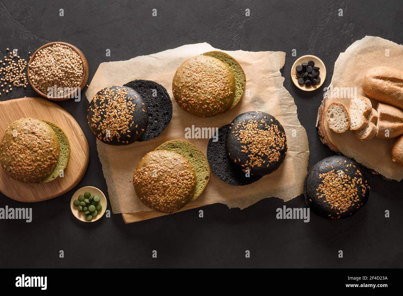 Pane vegano senza glutine e panini vari tipi con grano saraceno, spirulina, carbone su fondo nero. Vista dall'alto. Foto Stock
