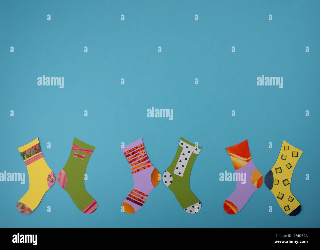 Concetto di Giornata Mondiale della sindrome di Down. Calzini diversi realizzati in carta su sfondo blu. Disposizione piatta, vista dall'alto. Spazio di copia. Foto Stock