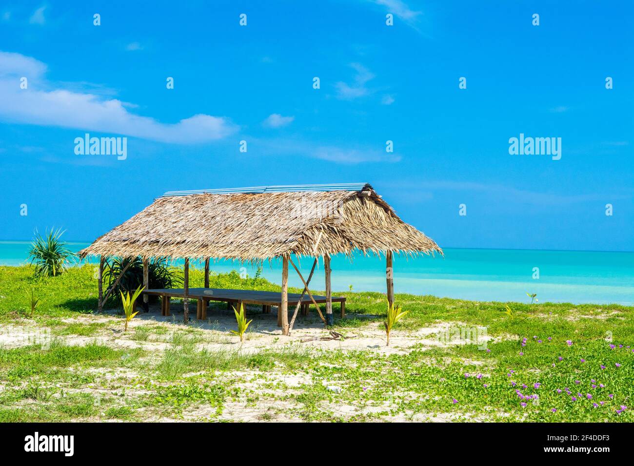 Lo splendido paesaggio del ristorante tropicale cafe' sotto i tetti di paglia sulla spiaggia di sabbia, ombreggiata da palme e piante tropicali Foto Stock