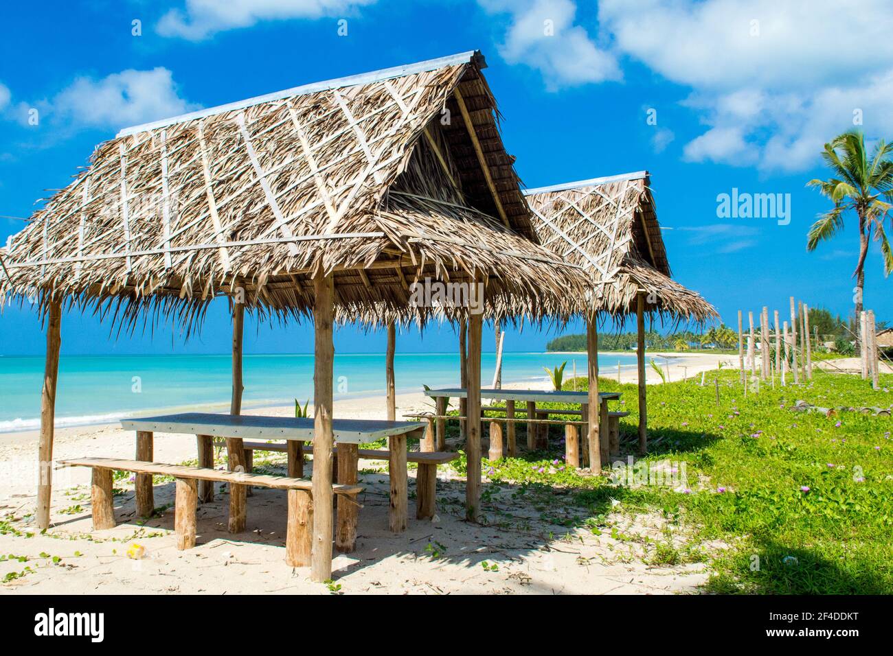 Lo splendido paesaggio del ristorante tropicale cafe' sotto i tetti di paglia sulla spiaggia di sabbia, ombreggiata da palme e piante tropicali Foto Stock