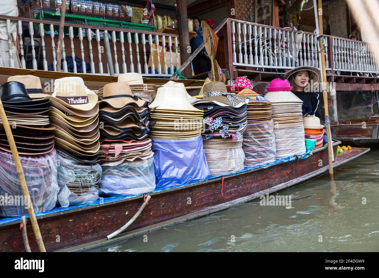 Donna che vende cappelli da una barca, mercato galleggiante Tha Kha, Bangkok, Thailandia Foto Stock