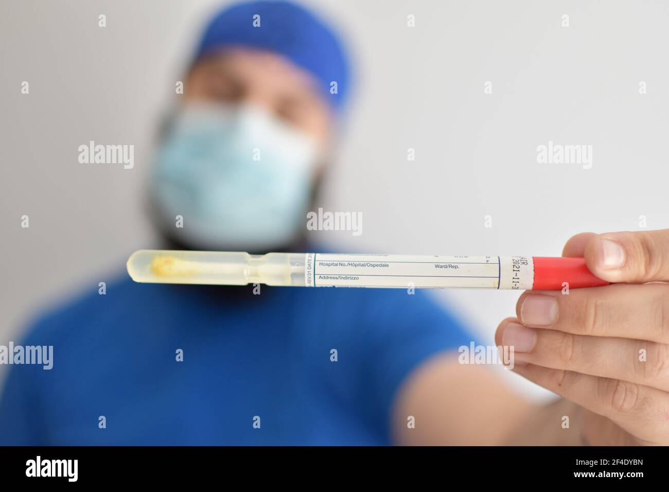 Infermiere che tiene un tubo. Test del rotavirus. Uomo che indossa una maschera facciale che afferra un campione di feci da esaminare in laboratorio Foto Stock