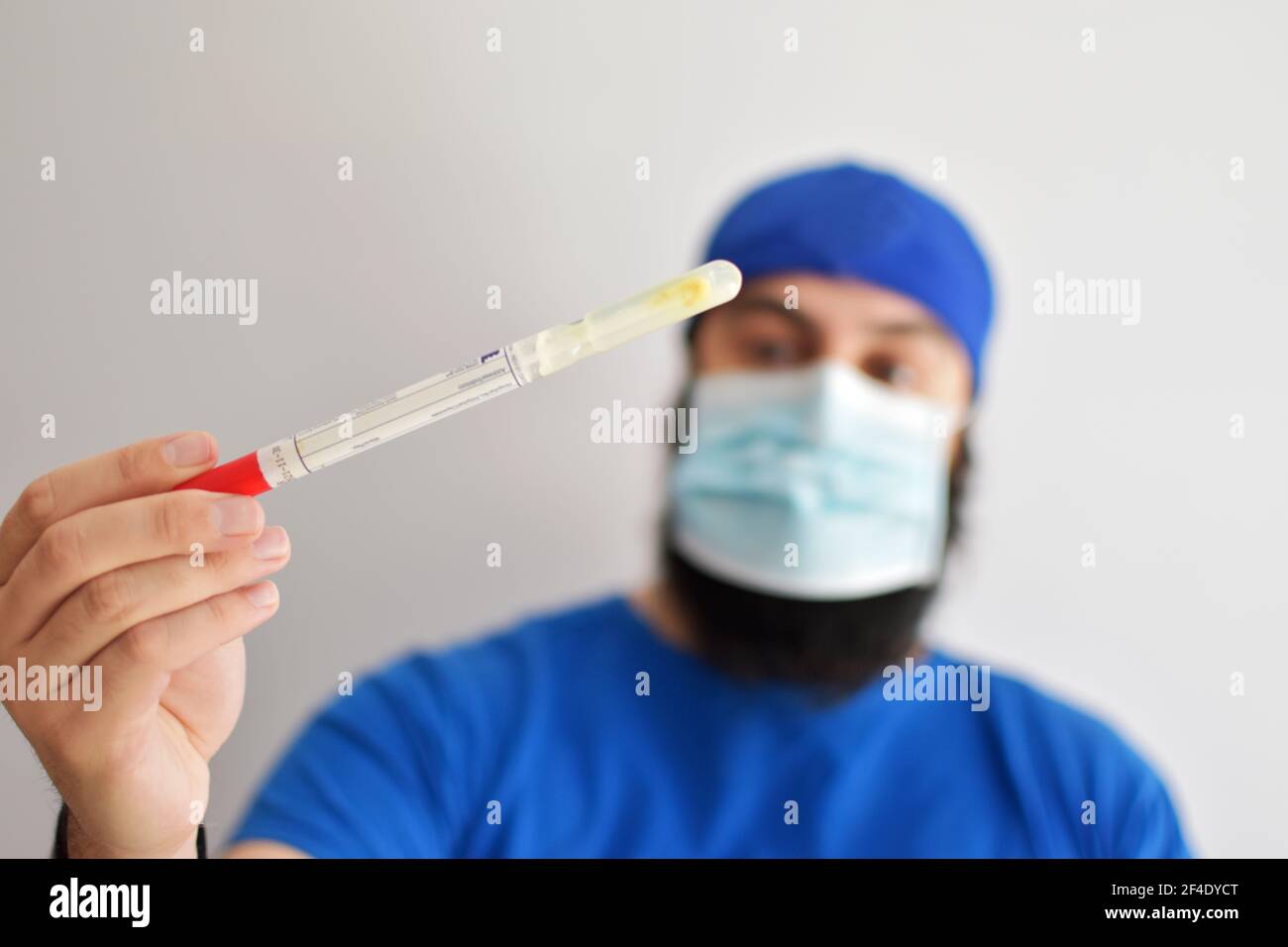 Infermiere che tiene un tubo. Test del rotavirus. Uomo che indossa una maschera facciale che afferra un campione di feci da esaminare in laboratorio Foto Stock