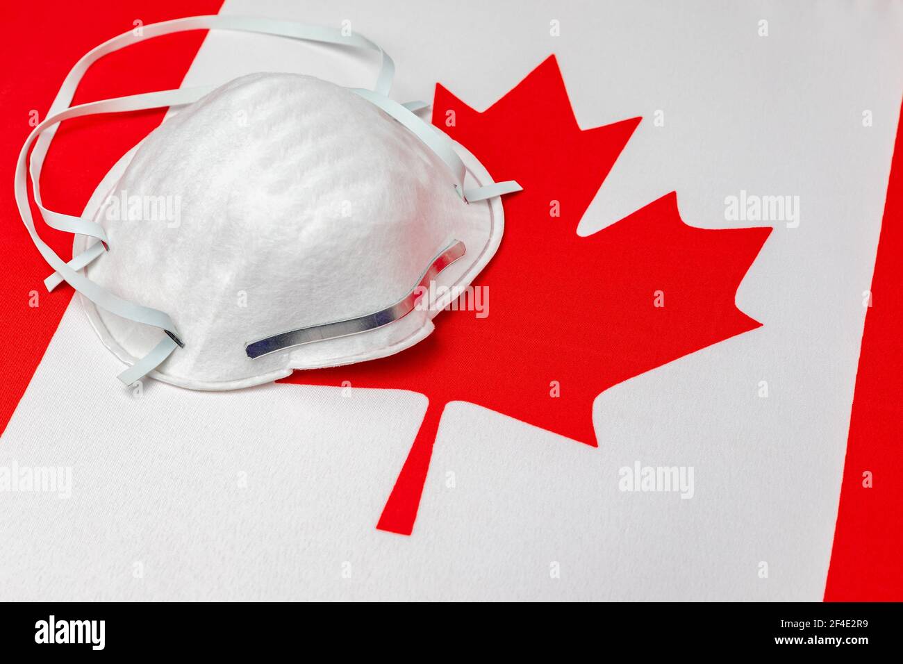 Bandiera Canada e maschera facciale N95. Concetto di Covid-19 coronavirus blocco, divieto di viaggio e crisi sanitaria Foto Stock