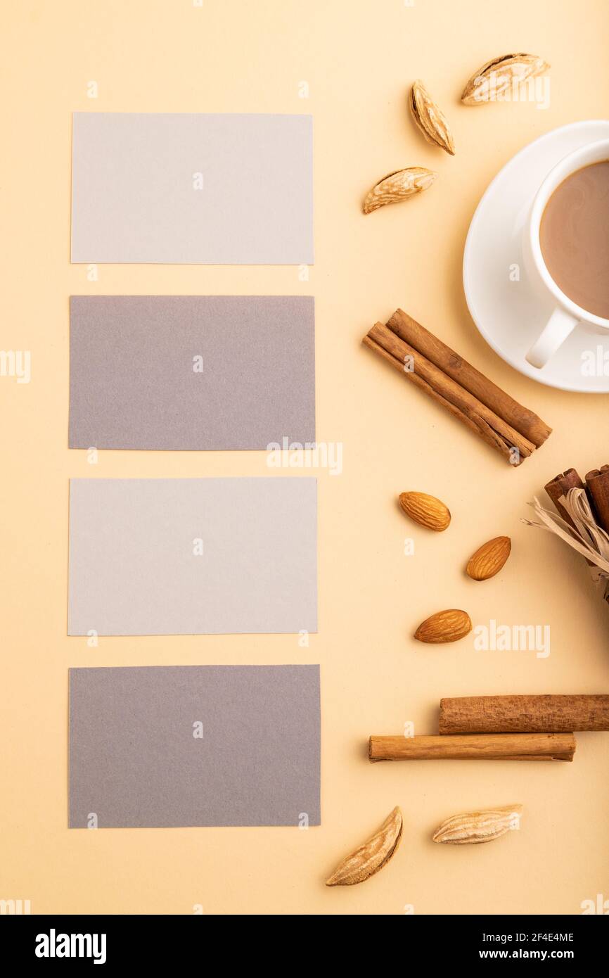 Composizione di biglietti da visita di carta grigia, mandorle, cannella e tazza di caffè. Mockup su sfondo arancione. Vuoto, vista dall'alto, vita still, posa piatta, COP Foto Stock