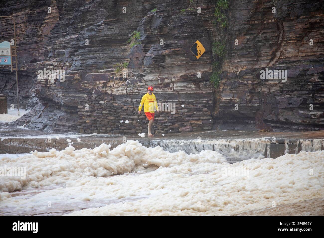 Avalon Beach, Sydney, Australia 21 marzo 2021.As inondazioni battter nuovo Galles del Sud la costa orientale surf batte la costa. Volontario surf salvataggio uomo controlla sulla spiaggia e guarda la schiuma di mare. Foto Stock