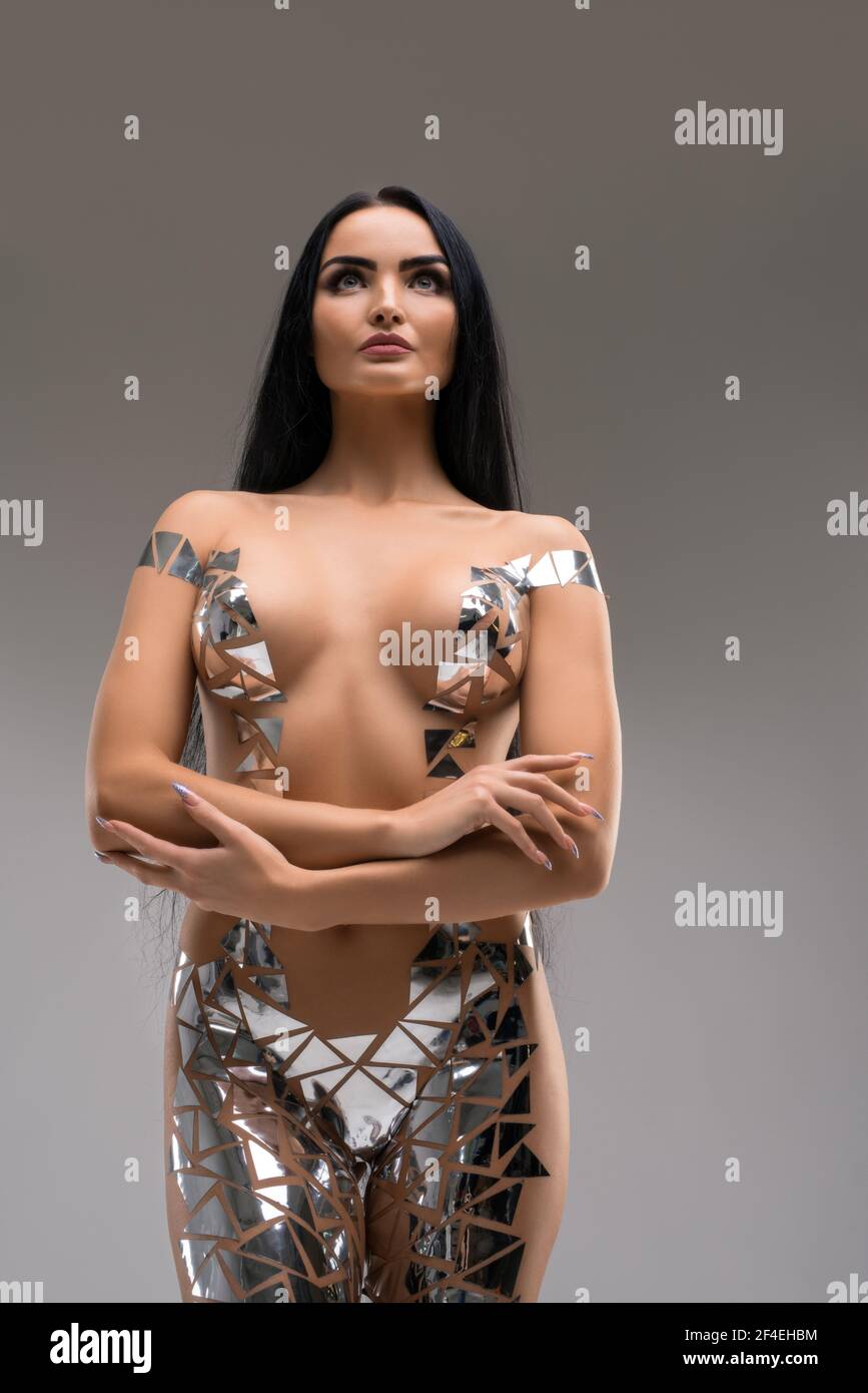 Donna seducente sottile in costume in lamina d'argento in studio Foto Stock