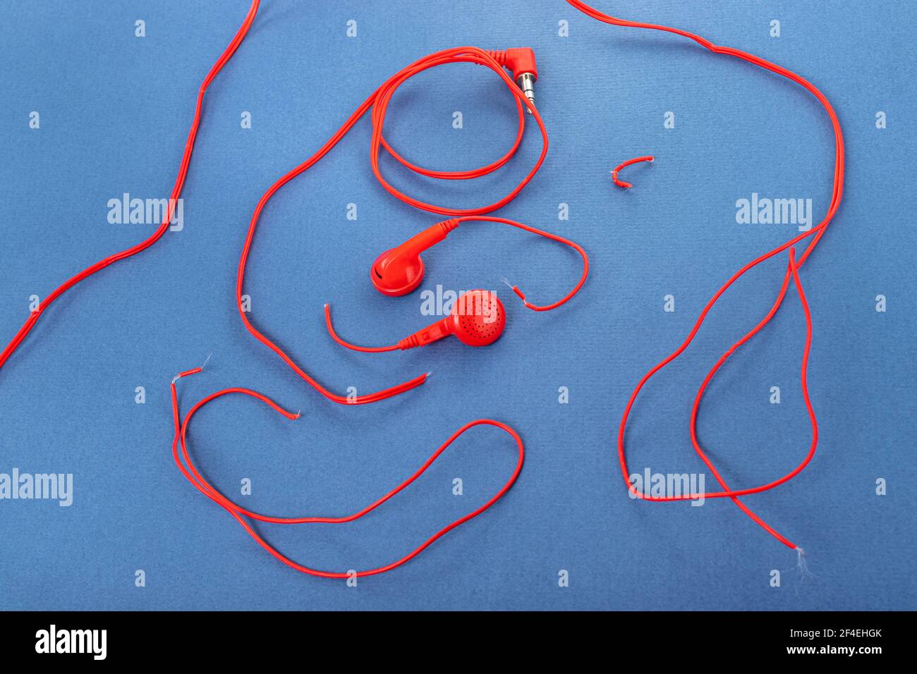 Cuffie su sfondo blu. Cuffie strappate. Riparazione dei dispositivi elettronici. Filo rotto. Foto Stock