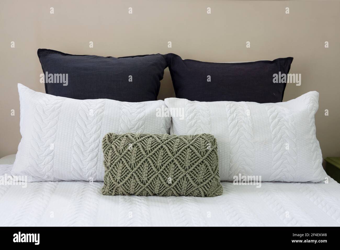 Una pila di cuscini su un letto in una camera moderna che offre comfort e riposo. Foto Stock