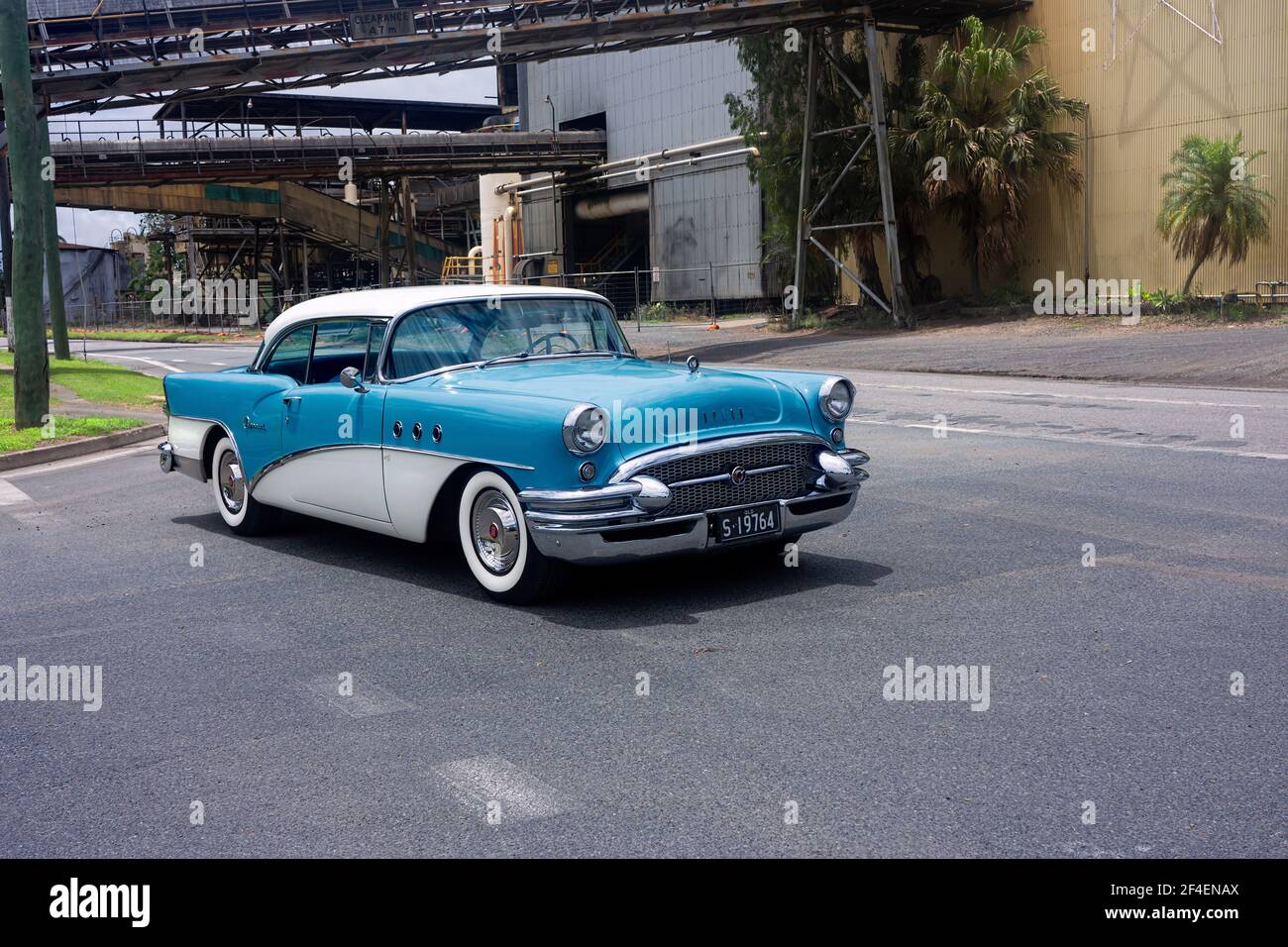 Una classica berlina americana restaurata Buick dal 1955 in blu e bianco contro uno sfondo industriale mulino con spazio di copia. Foto Stock