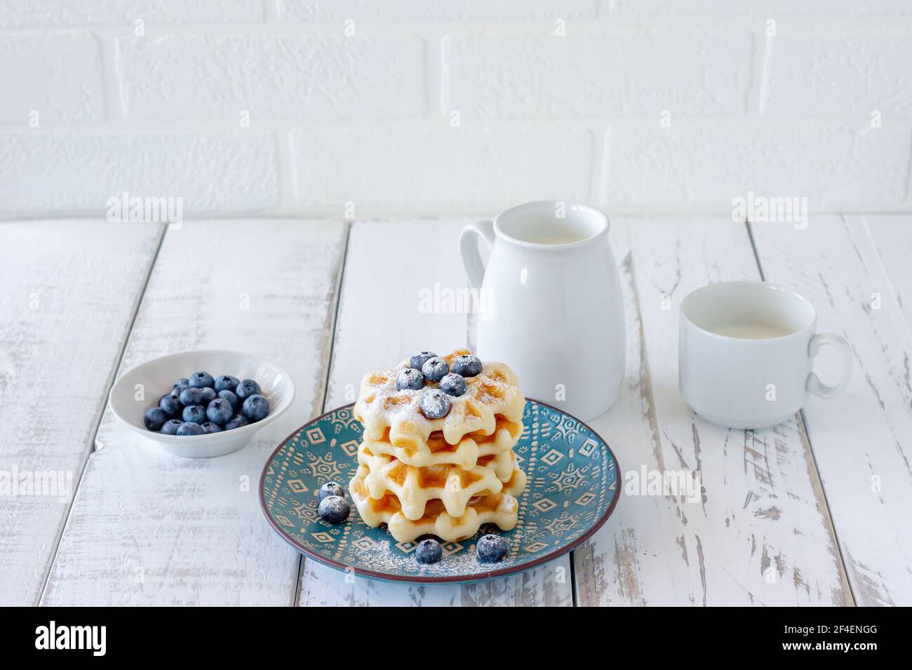 Waffle fatti in casa alla vaniglia con polvere di zucchero e mirtilli di cenere su un piatto, colazione perfetta per tutta la famiglia. Foto Stock