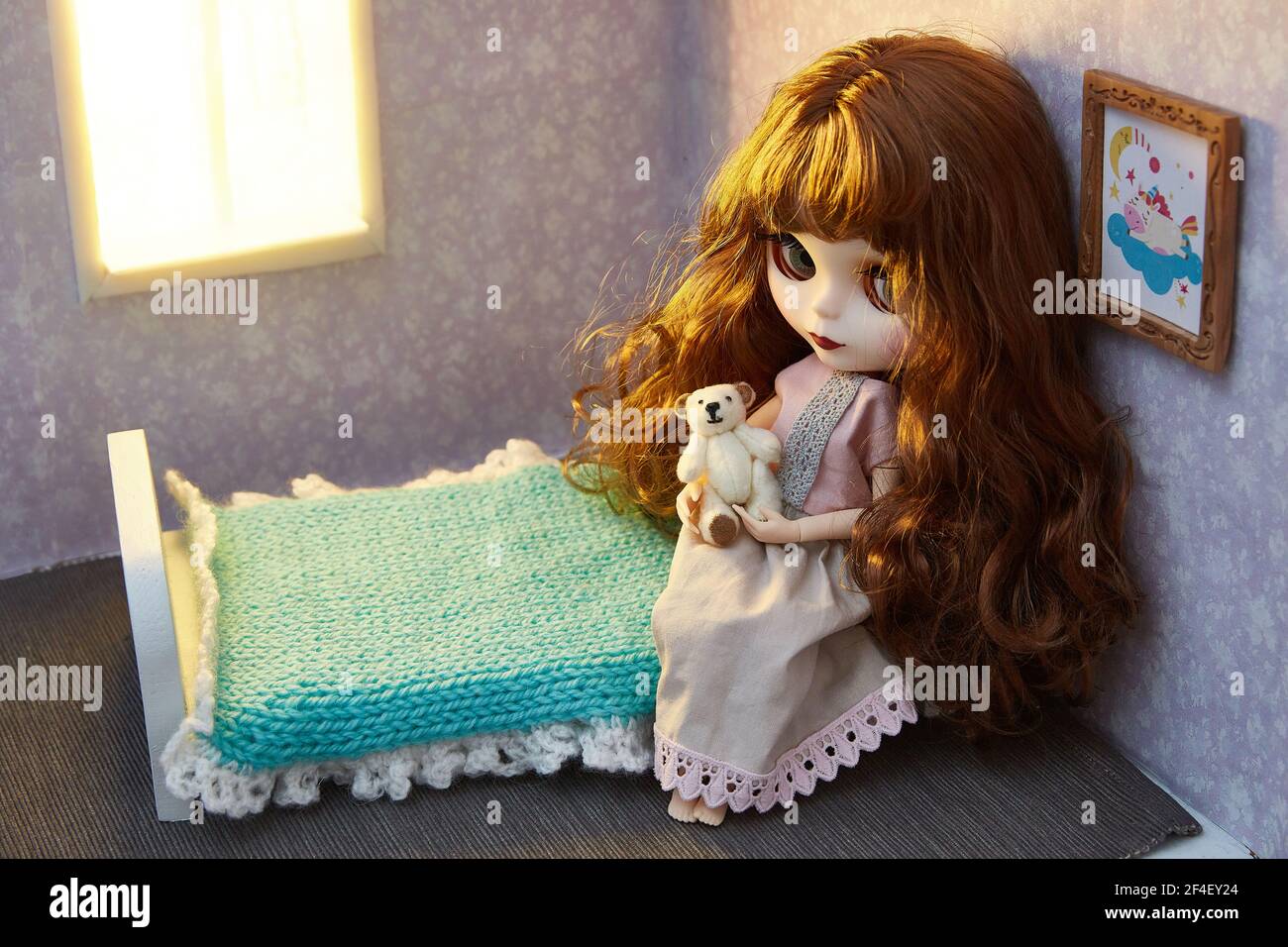 Una bambola nella casa di una bambola. Orsacchiotto in miniatura nelle mani di una bambola. Foto Stock