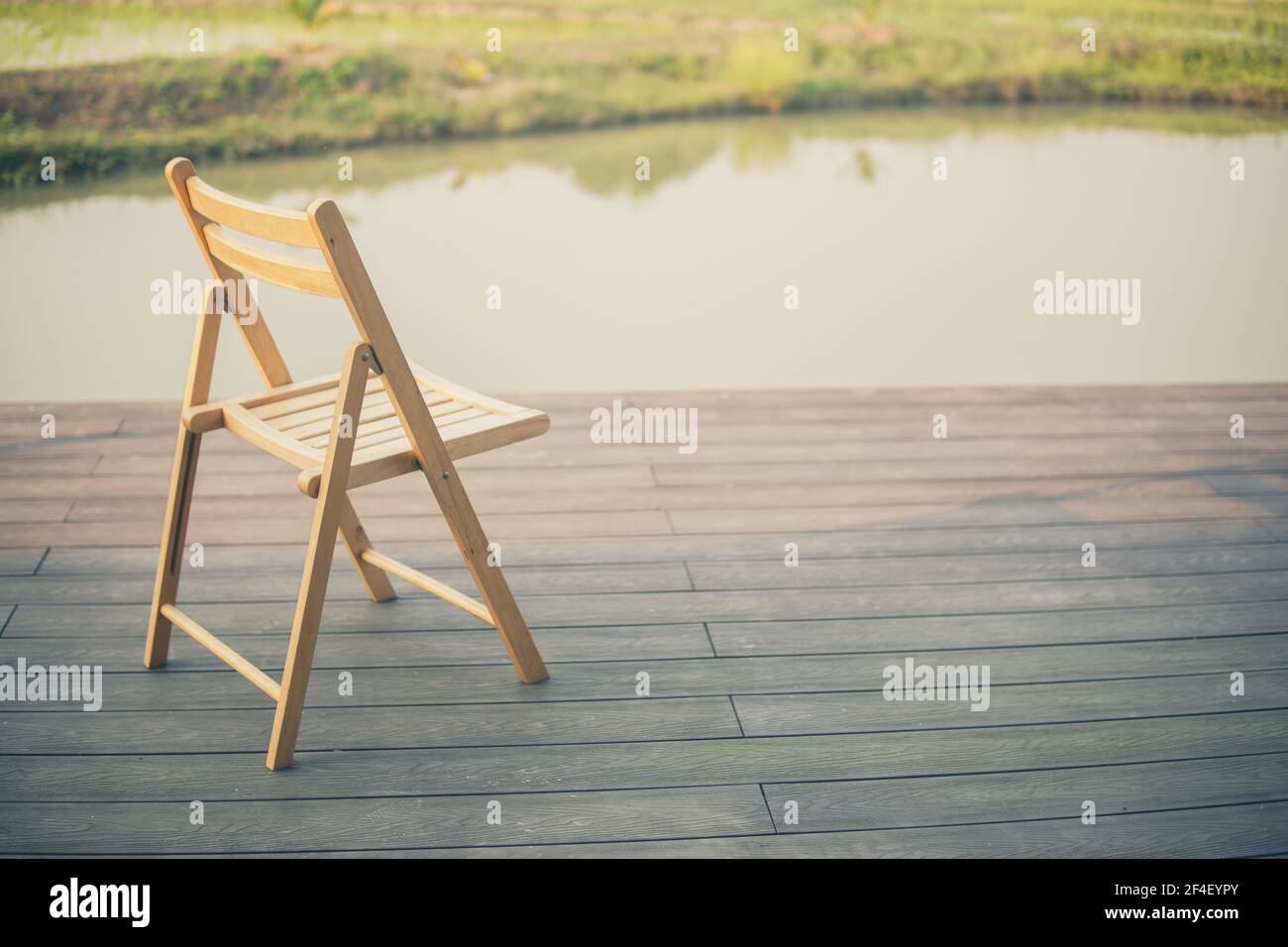 sedia in legno sul balcone terrazzo patio per riposare vicino al laghetto Foto Stock