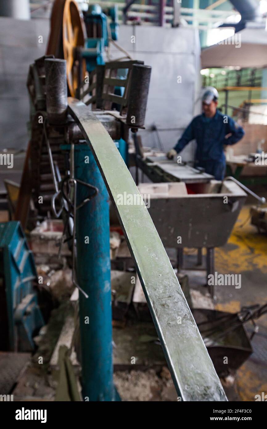 Impianto cavi e vergella in alluminio. Macchina per la produzione di aste e operatore di lavoro sfocato in background. Mettere a fuoco su Rod. Foto Stock
