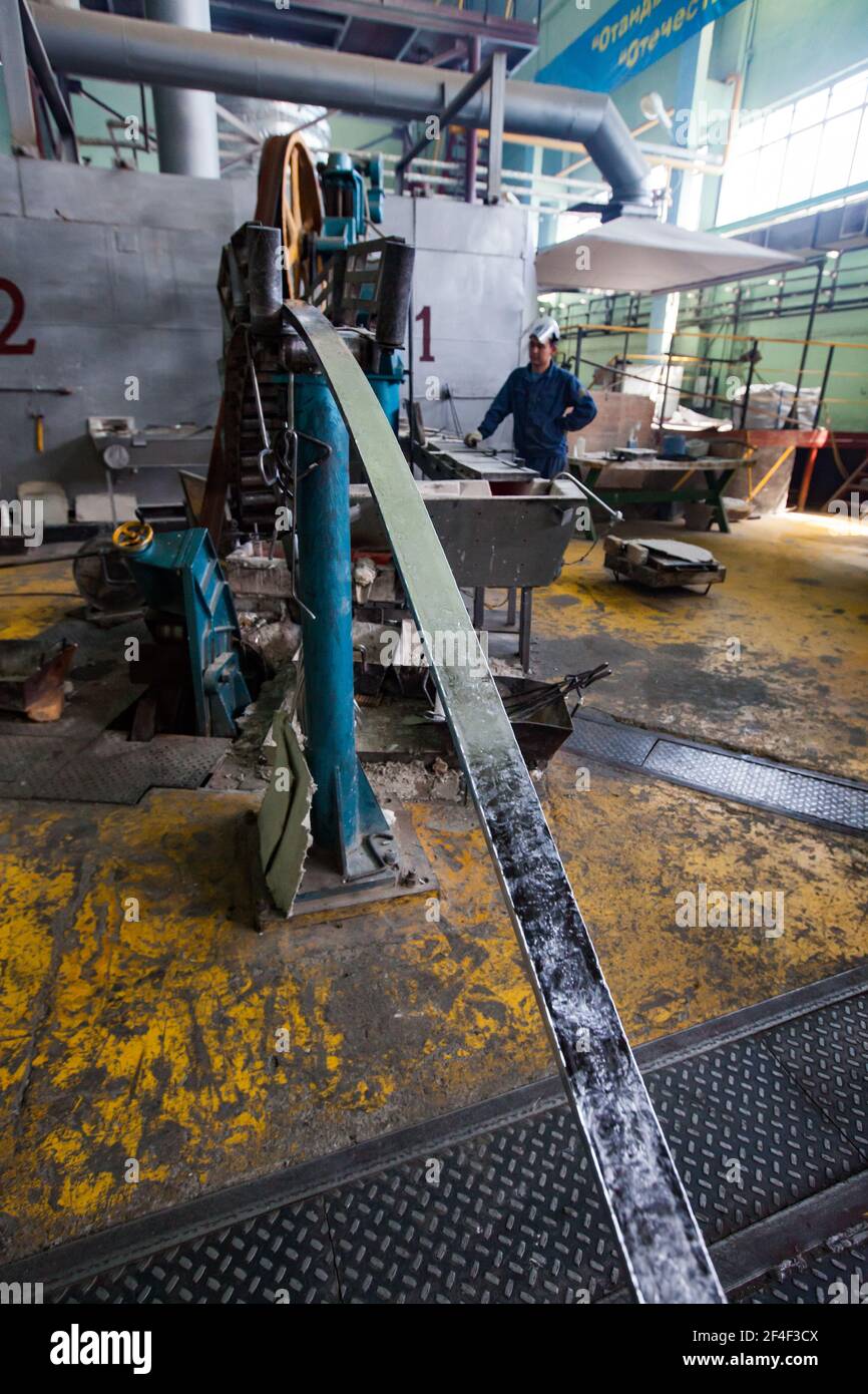 Impianto cavi e vergella in alluminio. Macchina per la produzione di aste e operatore di lavoro sfocato in background. Mettere a fuoco su Rod. Foto Stock