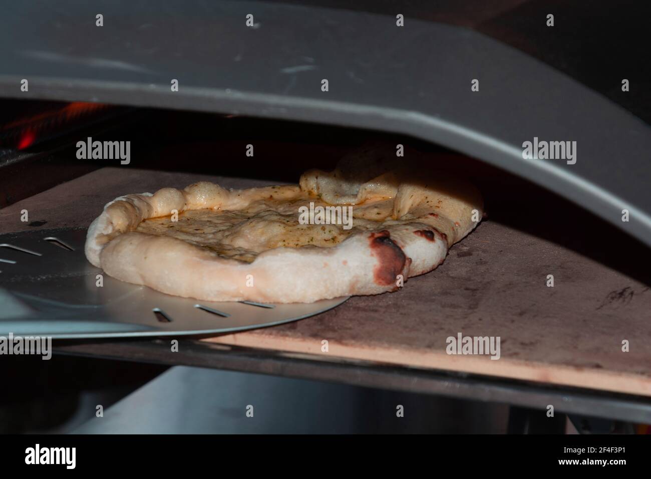 Chef cottura pizza pane nel forno a cucina privata AS uno sfondo mediterraneo Foto Stock