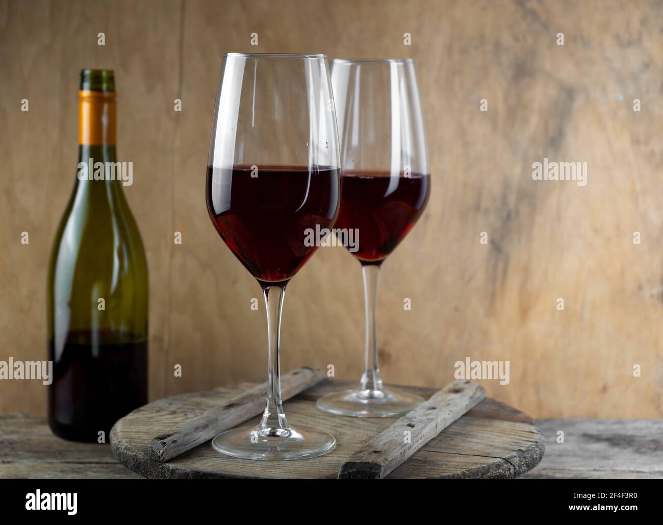 Due bicchieri di vino rosso. La bottiglia di vino è sul tavolo. Sfondo di vino. Vita morta. Bevanda alcolica in un bicchiere. Sfondo di legno Foto Stock