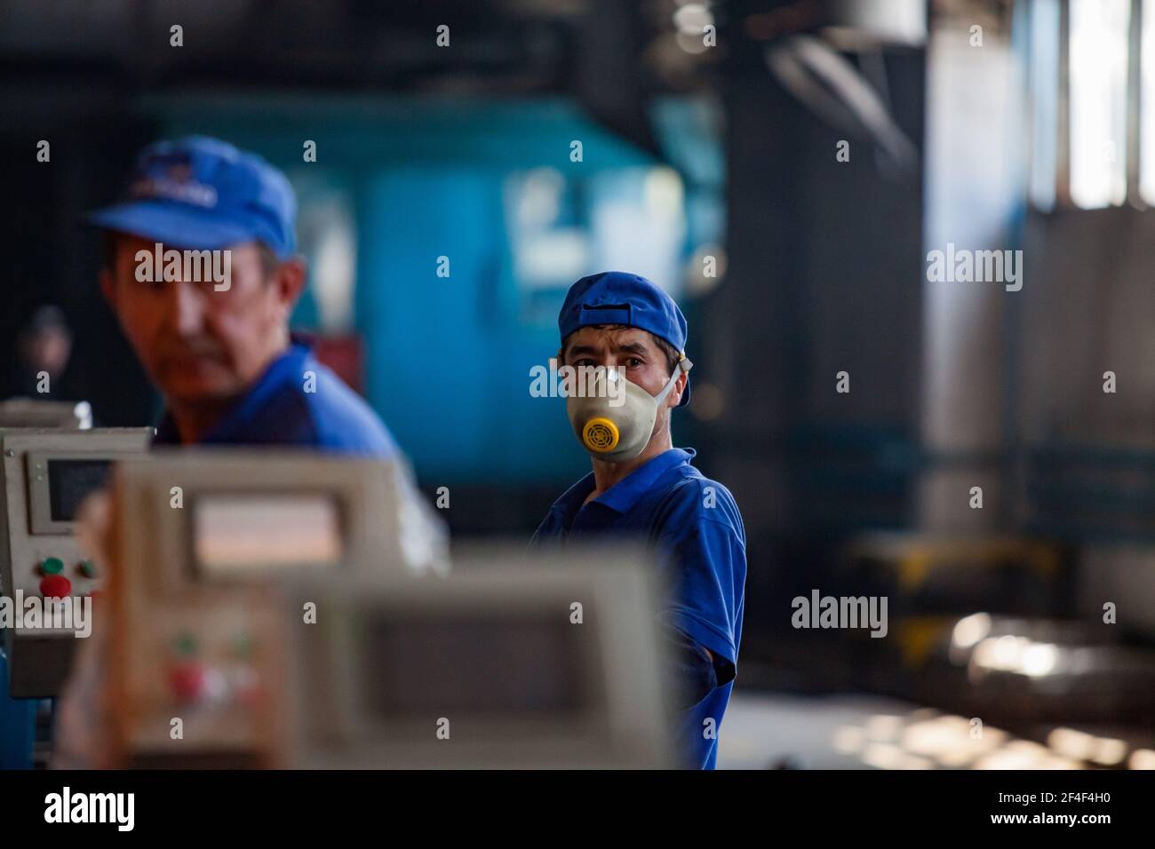 Taldykorgan, Kazakhstan - Giugno 06 2012: Impianto di riciclaggio degli accumulatori Kainar. Due lavoratori asiatici sulla linea di lavorazione. Lavoratore sinistro fuori fuoco. Foto Stock
