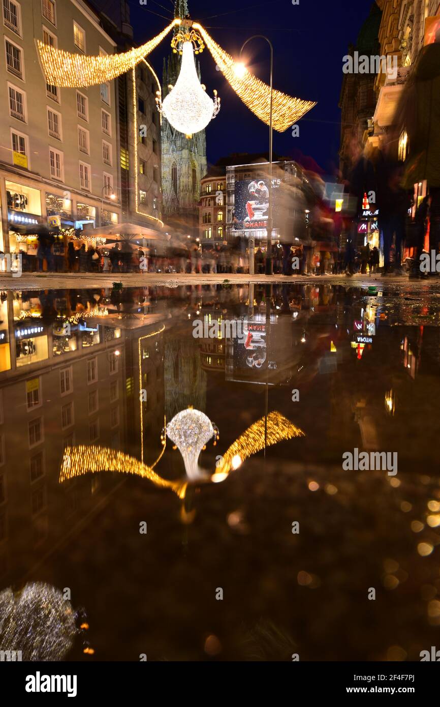 Vienna Graben Street nel periodo natalizio si riflette in una pozza d'acqua, mentre i turisti sono visite turistiche e shopping. Foto Stock