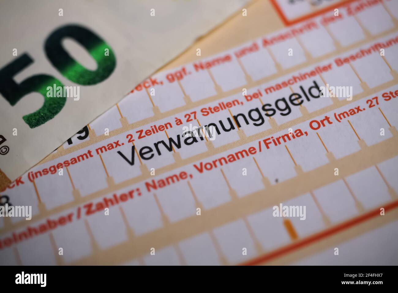 Viersen, Germania - 1 marzo. 2021: Makro closeup del modulo di bonifico bancario tedesco con biglietto di velocità (verwarnungsgeld) con banconote in euro Foto Stock