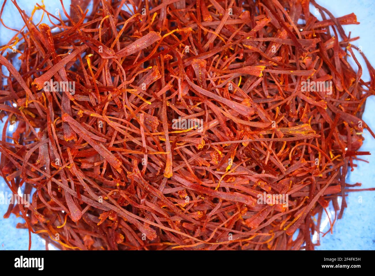 Makro chioseup di filetti di zafferano rossi essiccati isolati su blu piastra Foto Stock