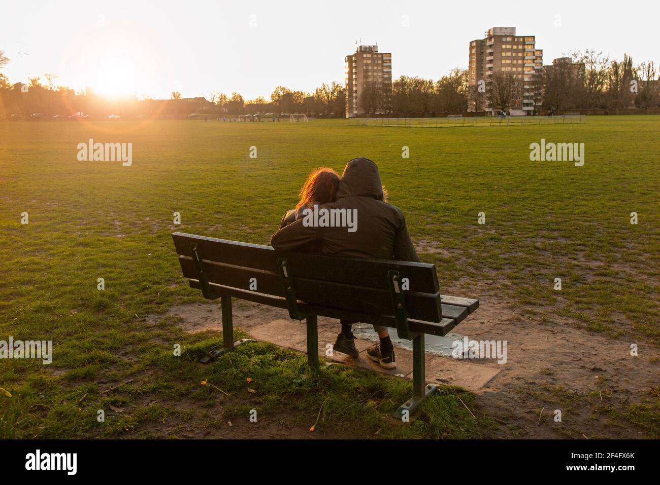 Una coppia seduta su una panchina in un parco urbano A Londra al sole del pomeriggio Foto Stock