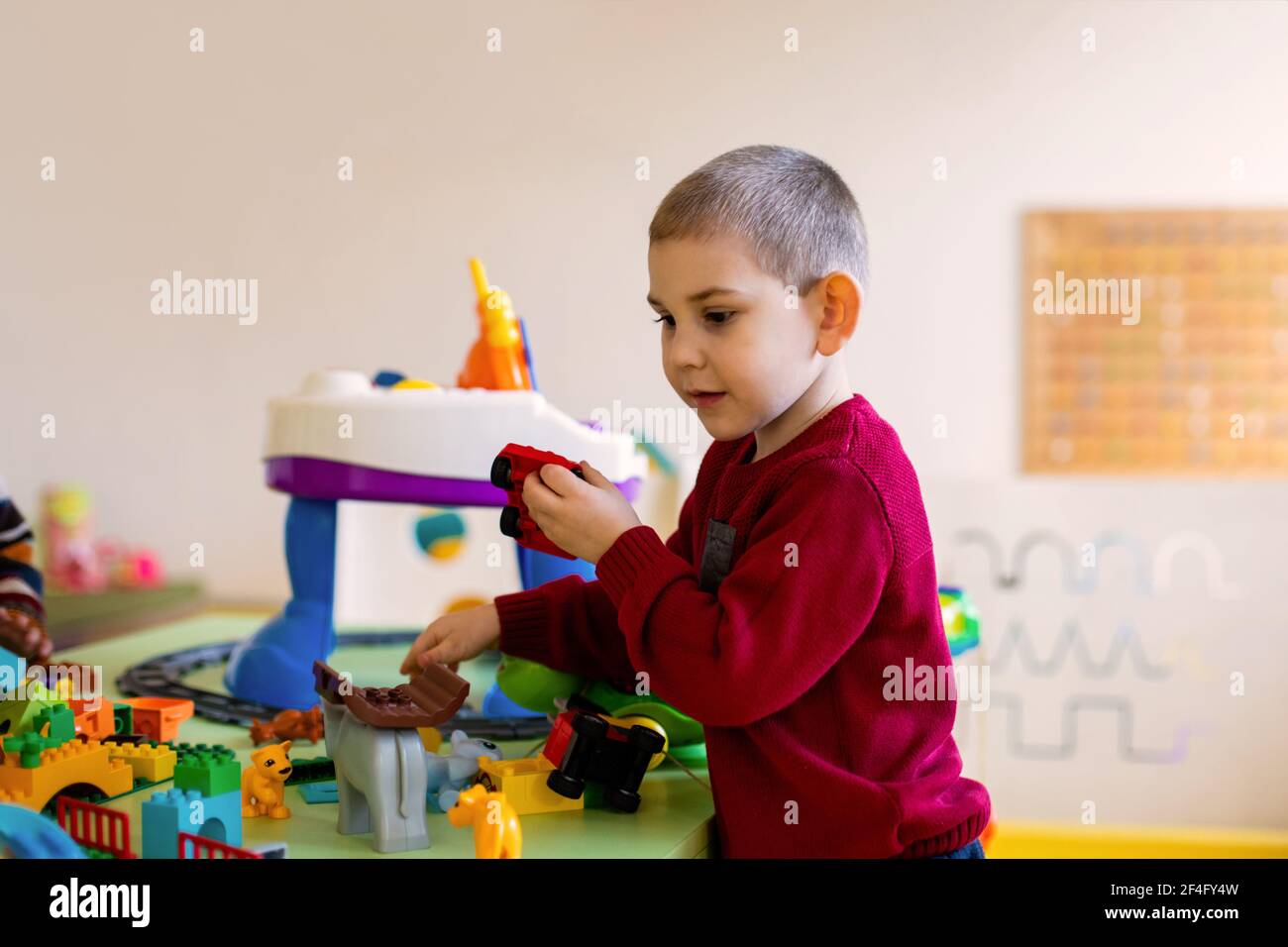 Il ragazzo prescolare immerso in un gioco con un costruttore Foto Stock