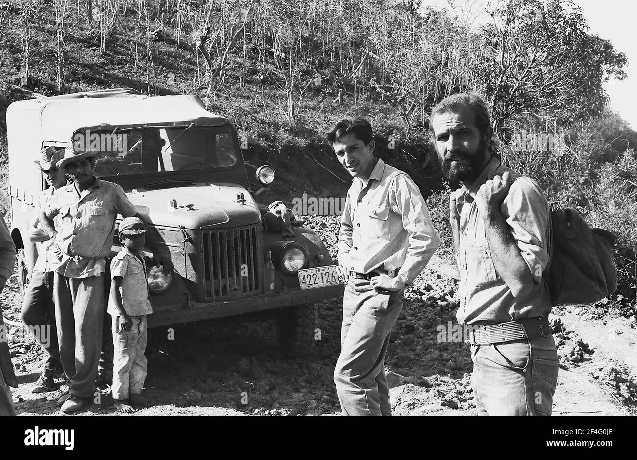 La gente è visibile in una strada sterrata con un veicolo in stile jeep mentre scende dalle montagne della Sierra Maestra, Cuba, 1963. Dalla collezione di fotografie Deena Stryker. () Foto Stock