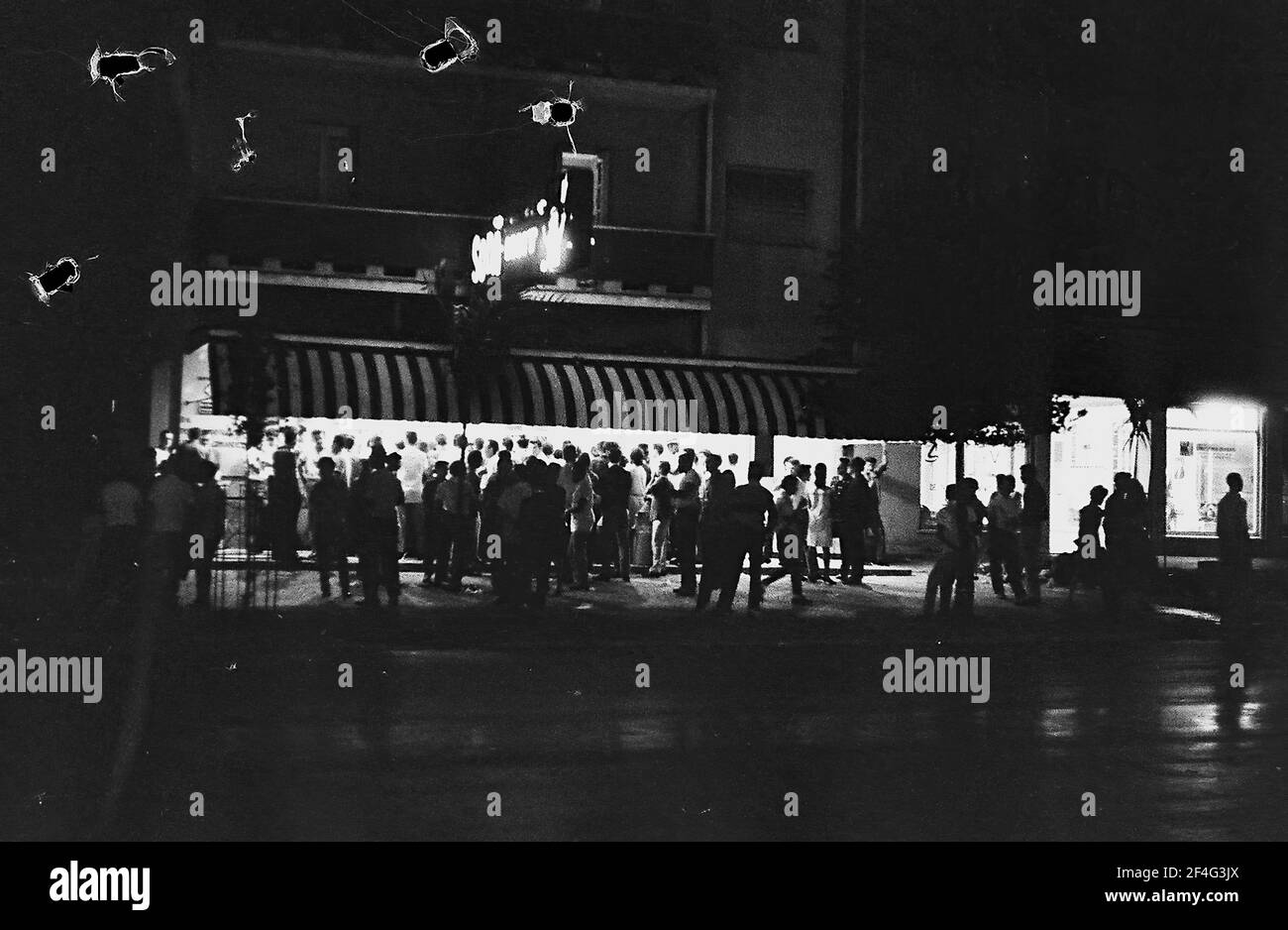 Vista notturna di un gran numero di clienti che si trovano fuori da una gelateria a Vedado, l'Avana, Cuba, 1964. Dalla collezione di fotografie Deena Stryker. () Foto Stock