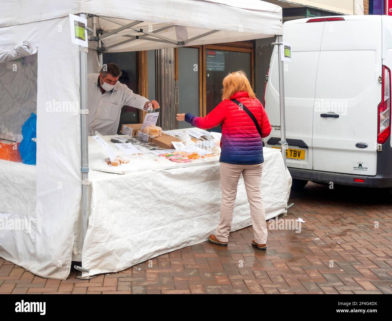Una donna cliente che acquista da una bancarella specializzata del mercato dei frutti di mare Nel Nord Yorkshire Foto Stock