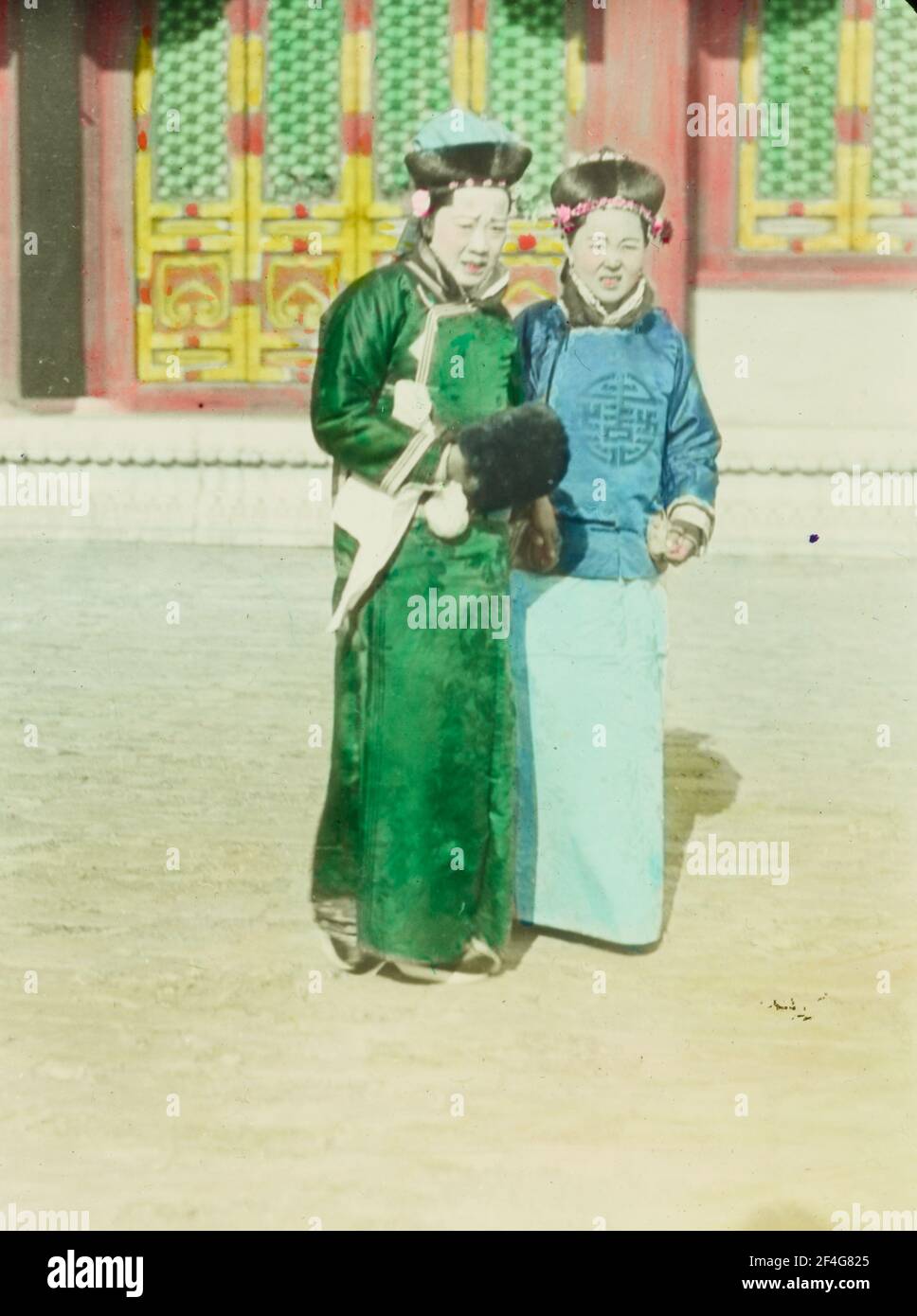 Foto a tutta lunghezza di due donne Manchu che indossano capelli liangbatou moderati e grimacing mentre si attraversa un cortile soleggiato nella Città Proibita, Pechino, Cina, 1918. Dalla collezione di fotografie di Sidney D. Gamble. () Foto Stock