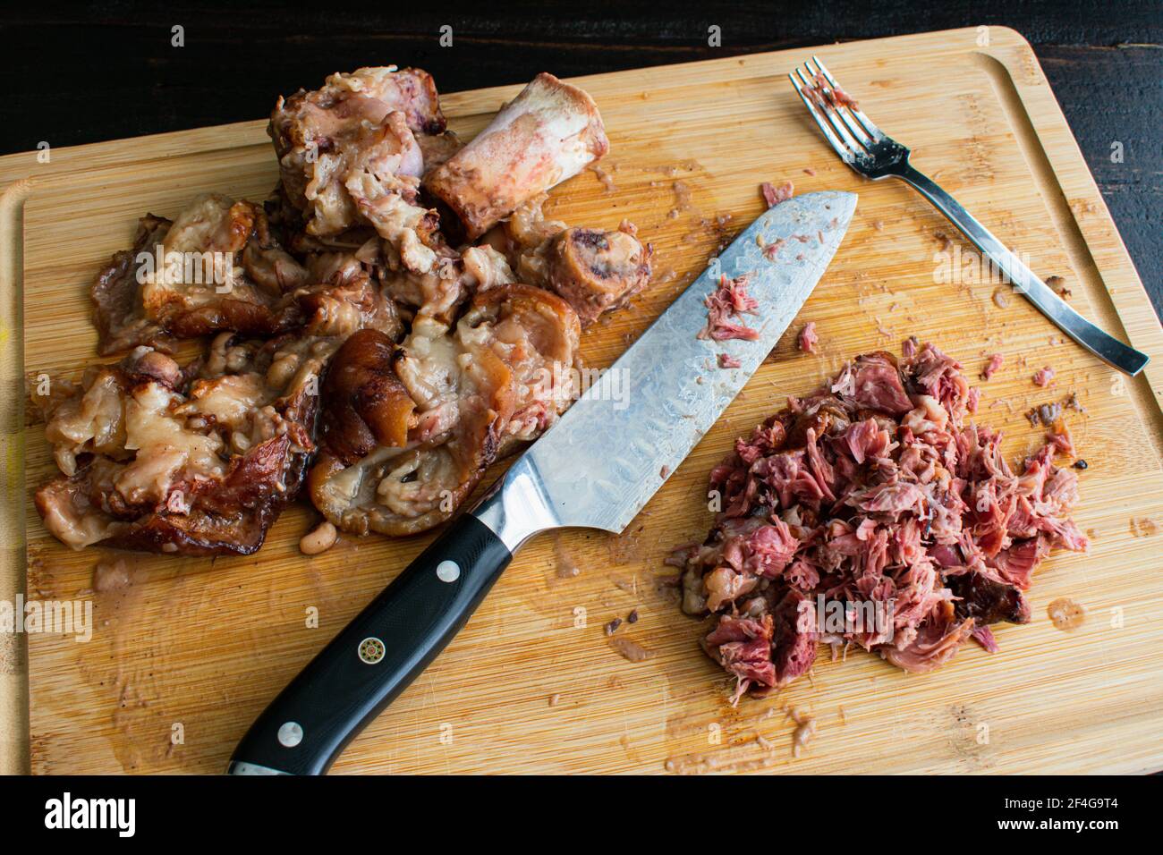 Taglio di carne da Ham Hocks affumicato: Carne tritata con la pelle e le ossa scartate su un tagliere di bambù Foto Stock