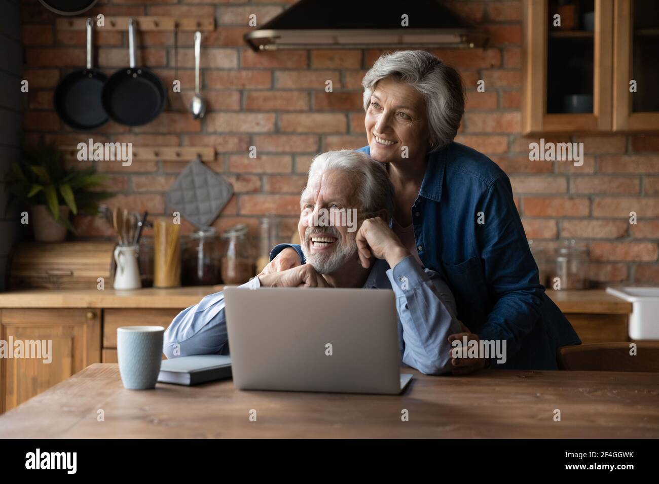 Bonding senior coppia abbraccio utilizzare il computer portatile guardare a distanza sognare Foto Stock