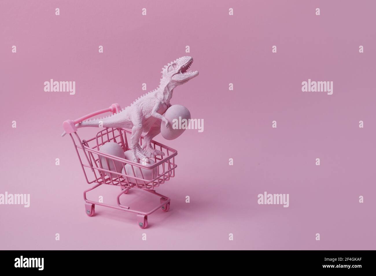 Dinosauro T rex con carrello e uova su sfondo rosa. Concetto di vendita mega di Pasqua. Foto Stock