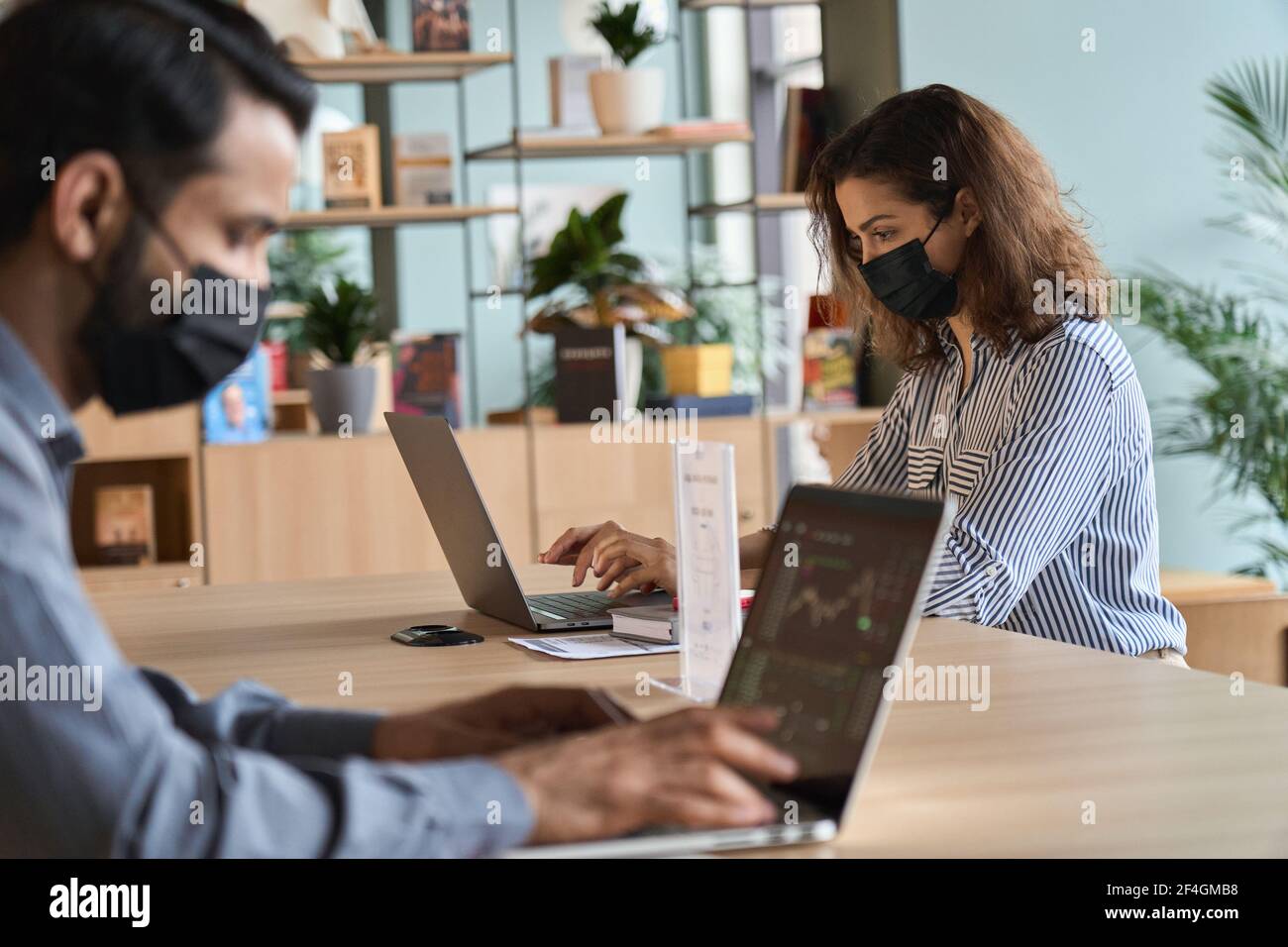 Giovane donna latina che indossa la maschera facciale che lavora su un computer portatile mantenendo una distanza di sicurezza. Foto Stock Giovane donna latina che indossa la maschera facciale che lavora su un computer portatile mantenendo una distanza di sicurezza. Foto Stock