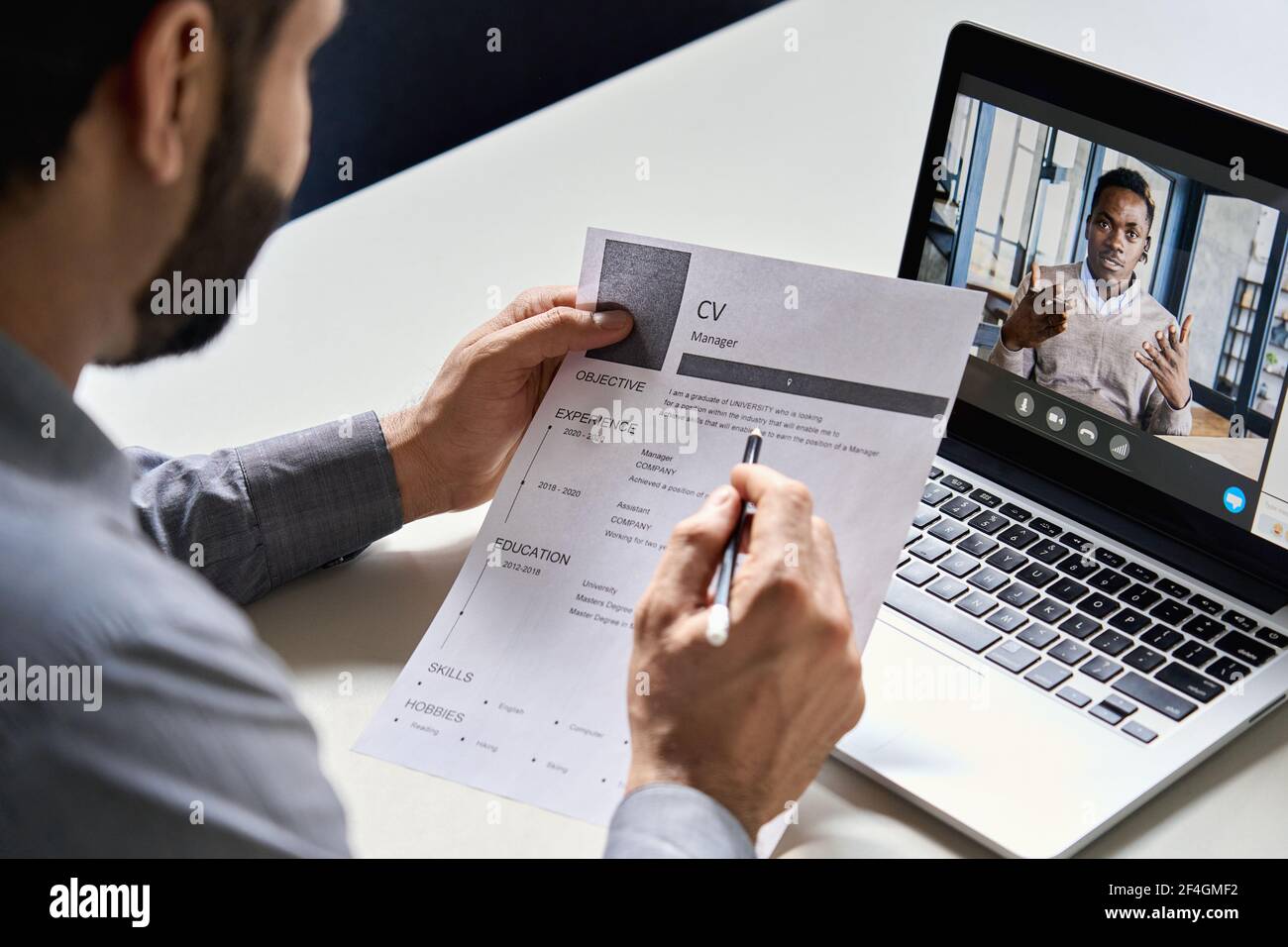Datore di lavoro indiano che legge cv durante l'intervista virtuale di lavoro con il candidato africano. Foto Stock