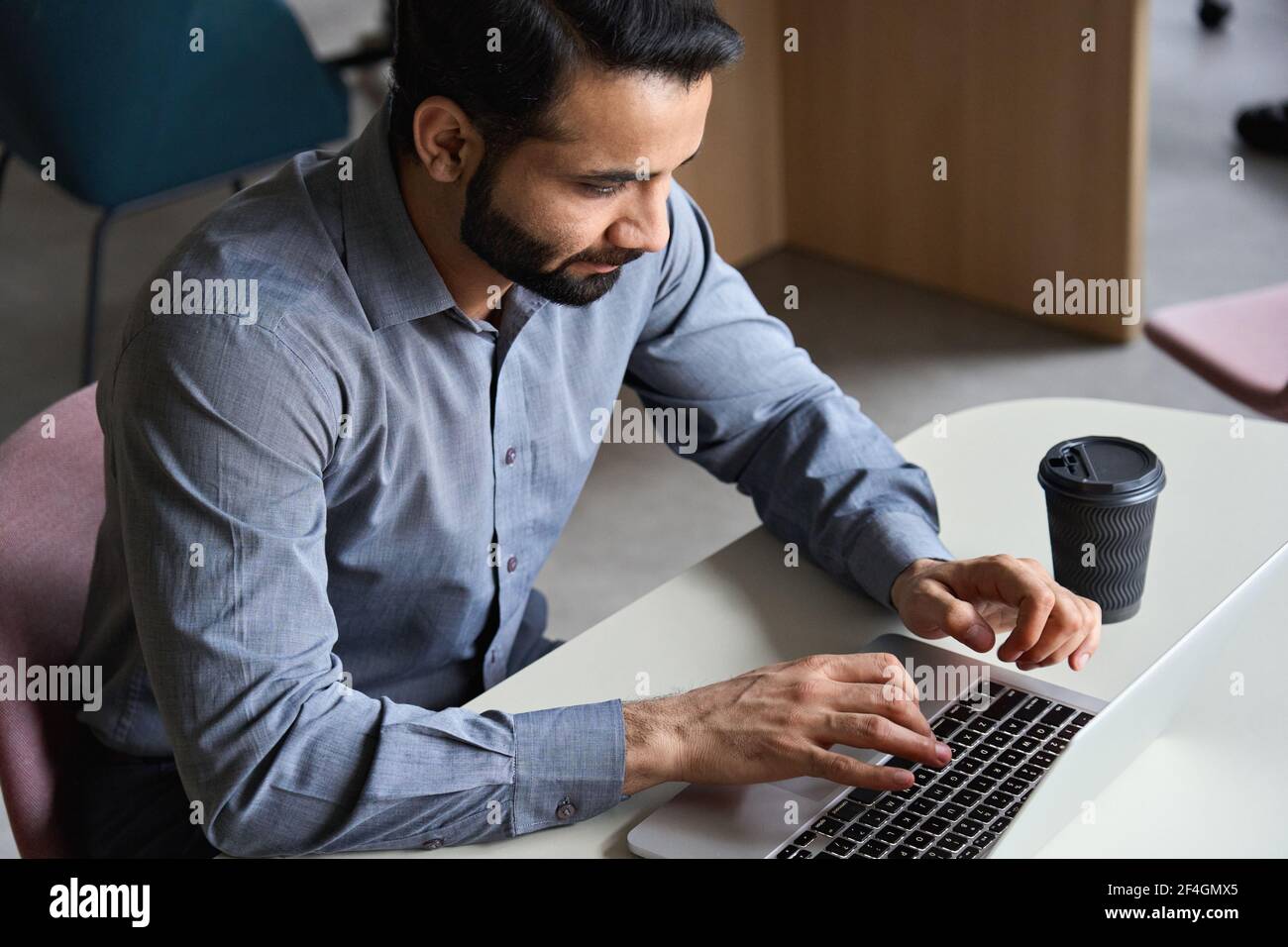 Uomo d'affari indiano che lavora o sta studiando la digitazione sul laptop in ufficio domestico. Foto Stock