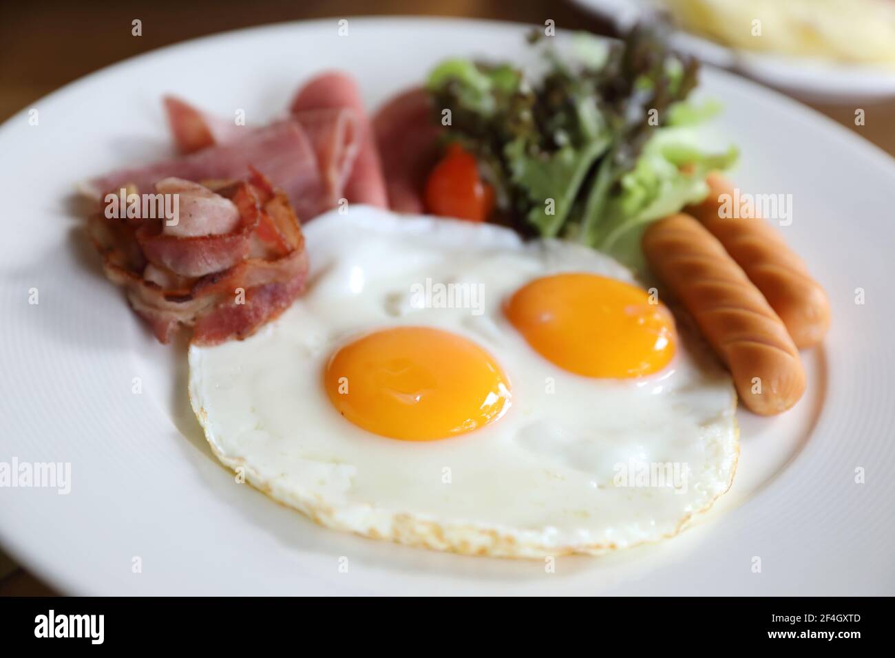 Set colazione con uova fritte, pancetta, salsicce, fagioli, pane tostato, insalata fresca e frutta sulla tavola di legno Foto Stock