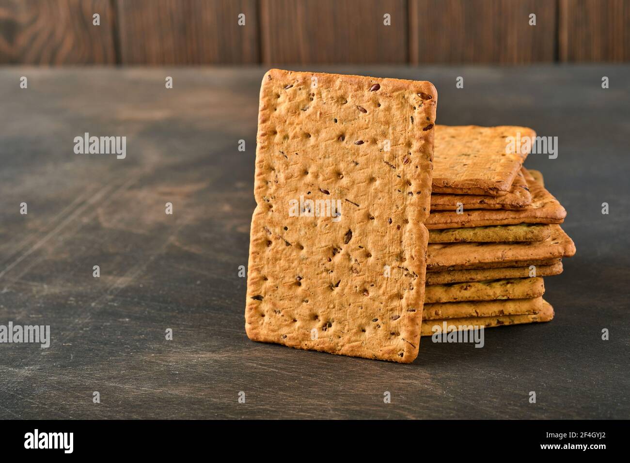 Cracker con semi di lino e crusca di avena forma rettangolare per una dieta sana, dietetica ed equilibrata su fondo di legno scuro. Snack per una corretta alimentazione Foto Stock
