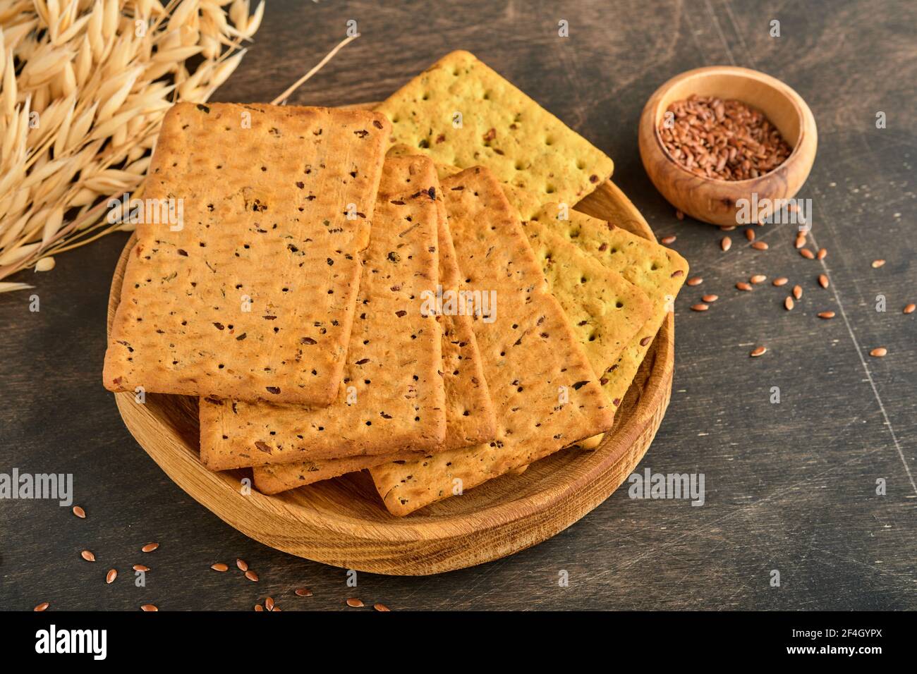 Cracker con semi di lino e crusca di avena forma rettangolare per una dieta sana, dietetica ed equilibrata su fondo di legno scuro. Snack per una corretta alimentazione Foto Stock