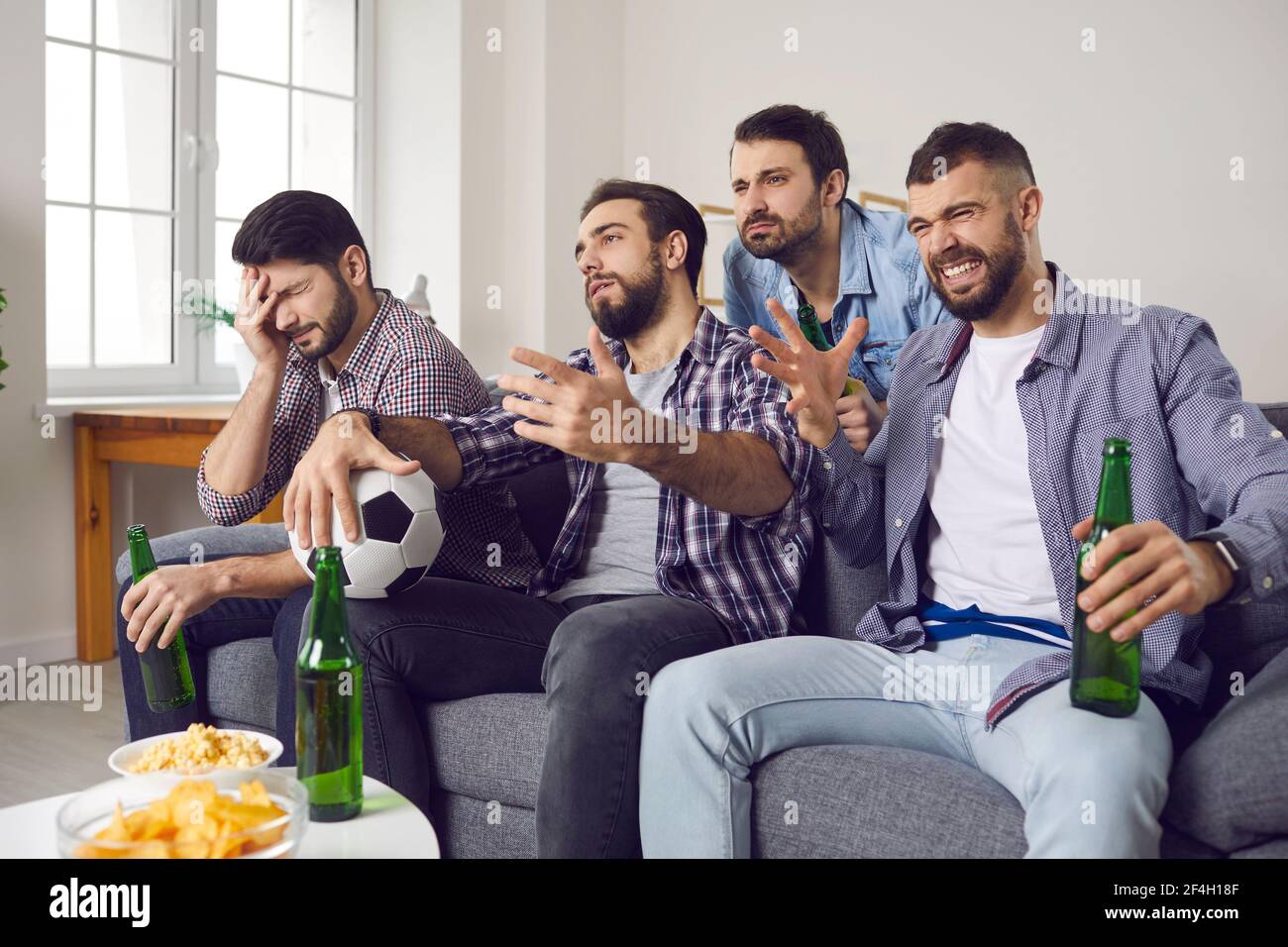 Sconvolgere i giovani appassionati di sport seduti sul divano e guardare terribile Partita di calcio in TV Foto Stock