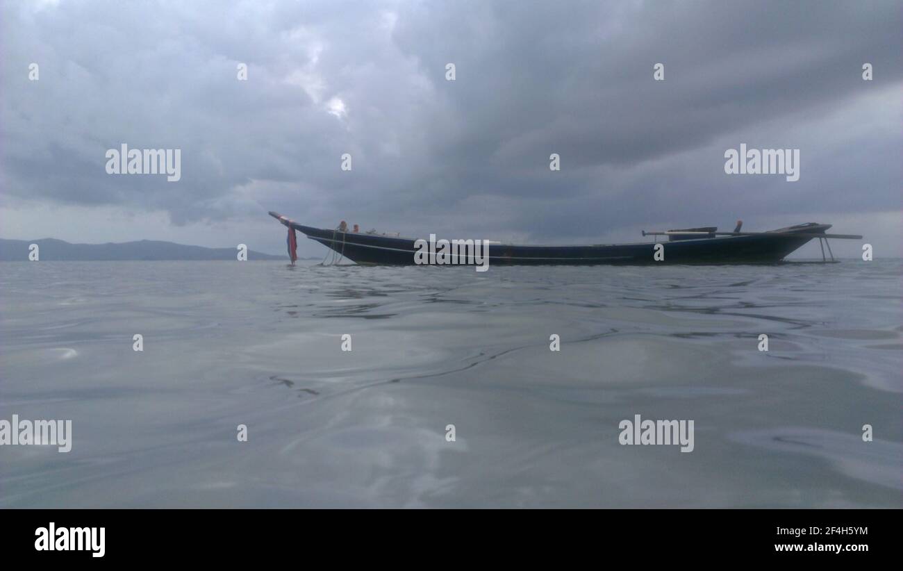 Vista sul livello dell'acqua di una lunga barca a coda di fronte Di una tempesta imminente a Ko Lanta Foto Stock