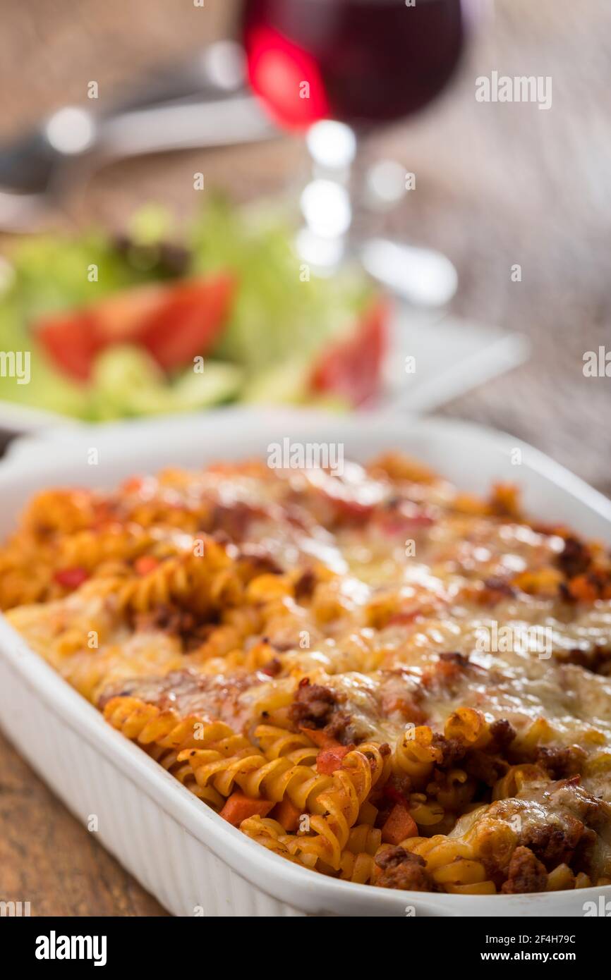 pasta gratinata con insalata su legno Foto Stock