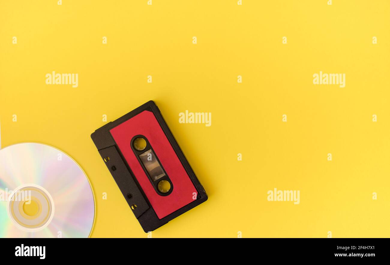 Cassetta audio nera e disco su sfondo giallo. 80 s. Vista dall'alto. Disposizione piatta. Foto Stock