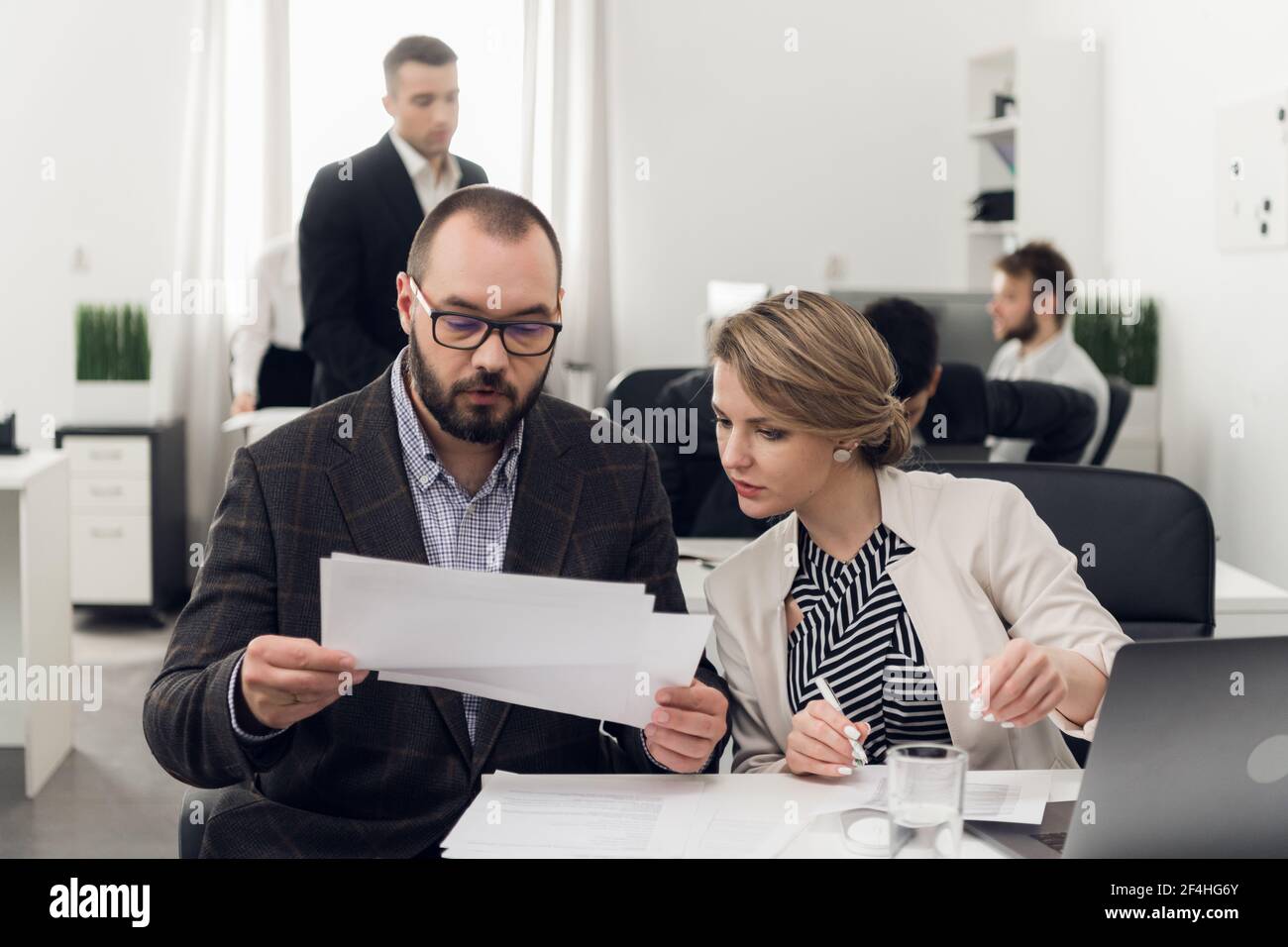 Un giovane manager consegna documenti cartacei al responsabile del reparto HR dell'ufficio della società di leasing per la verifica. Foto Stock