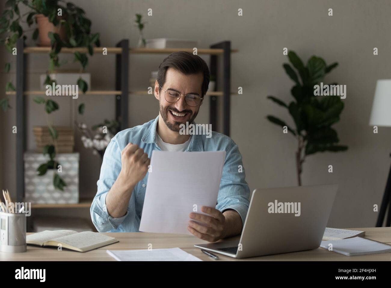 Uomo felice che indossa occhiali leggere buone notizie, mostrando sì gesto Foto Stock