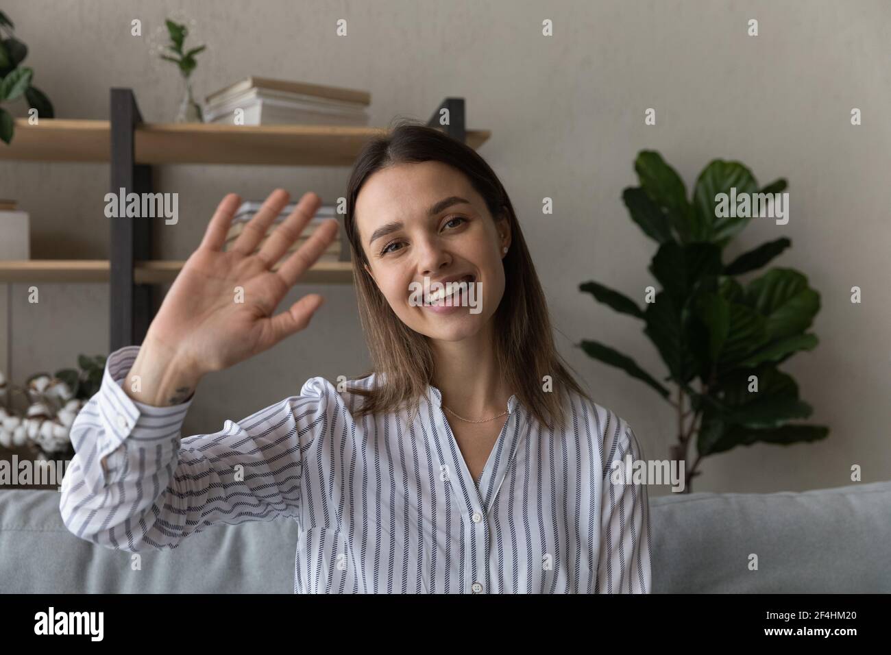 Foto ritratto di testa sorridente donna che sventola la mano alla fotocamera Foto Stock