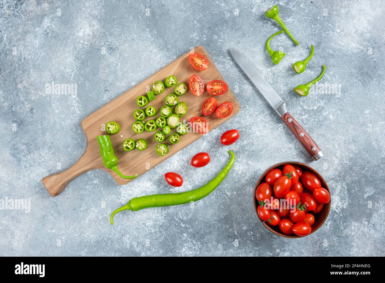 Peperoni e pomodori jalapeno a fette su tavola di legno Foto Stock